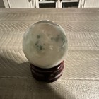 Polished Crystal stone Healing Sphere Ball With Green Inclusions On Wooden Stand